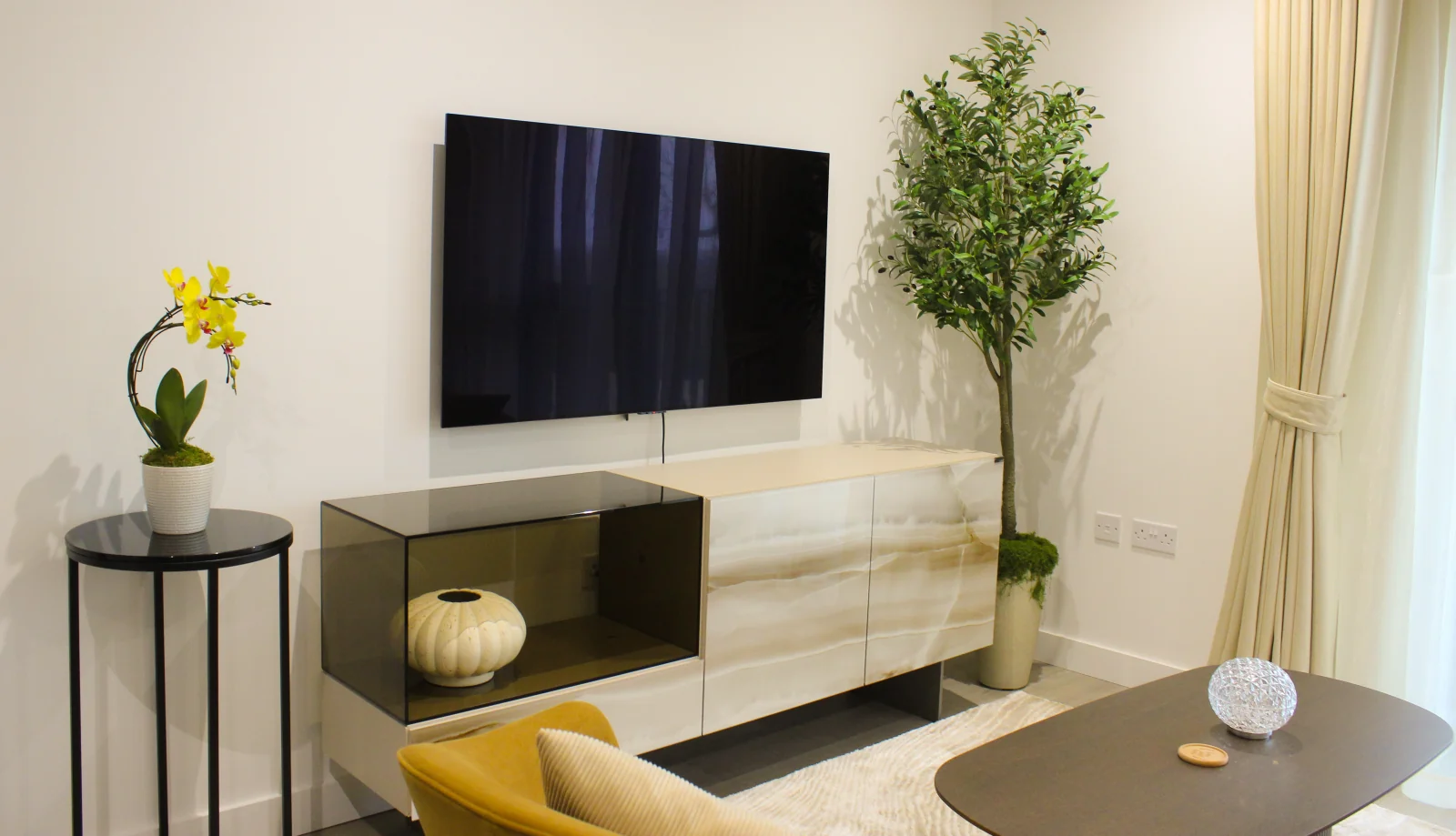 A sunlit, minimalist living space with soft textures and warm wood accents, creating a calm home sanctuary.